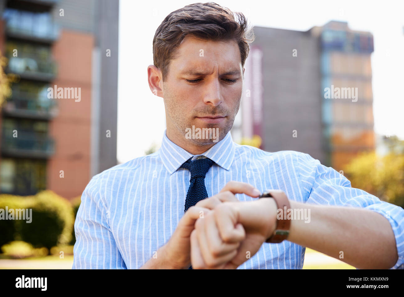 Geschäftsmann zu Fuß durch City Park suchen Bei Smart Watch Stockfoto