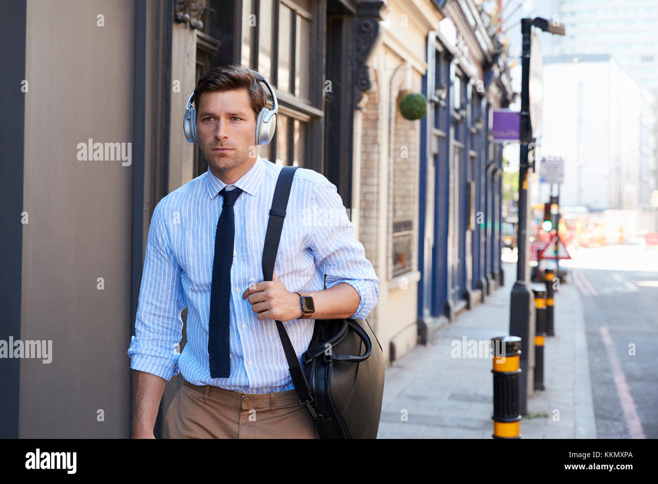 Unternehmer tragen die drahtlosen Kopfhörer zu Fuß zu arbeiten Stockfoto