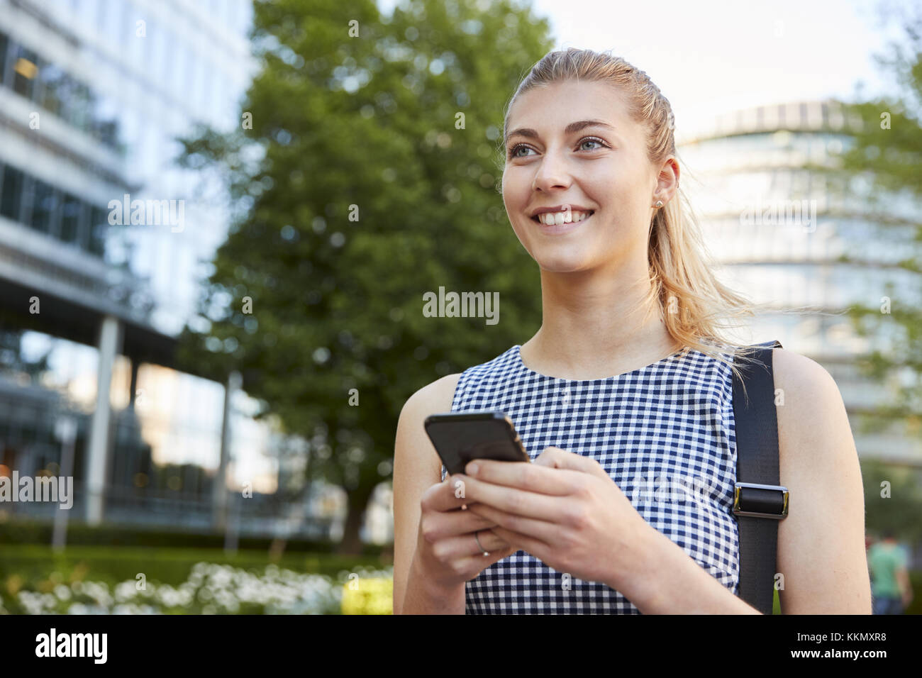 Geschäftsfrau zu Fuß zur Arbeit in Stadt in Handy suchen Stockfoto