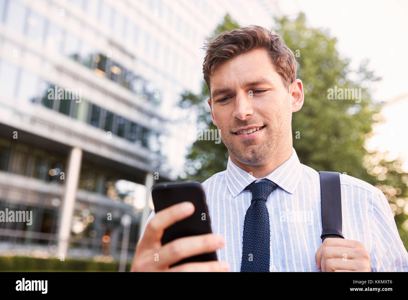 Geschäftsmann zu Fuß zur Arbeit in Stadt in Handy suchen Stockfoto