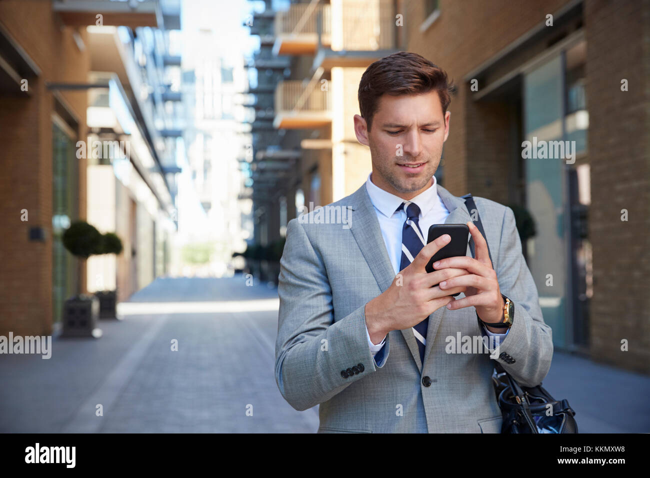 Geschäftsmann zu Fuß zur Arbeit in Stadt in Handy suchen Stockfoto