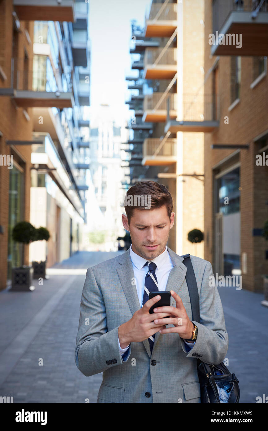 Geschäftsmann zu Fuß zur Arbeit in Stadt in Handy suchen Stockfoto