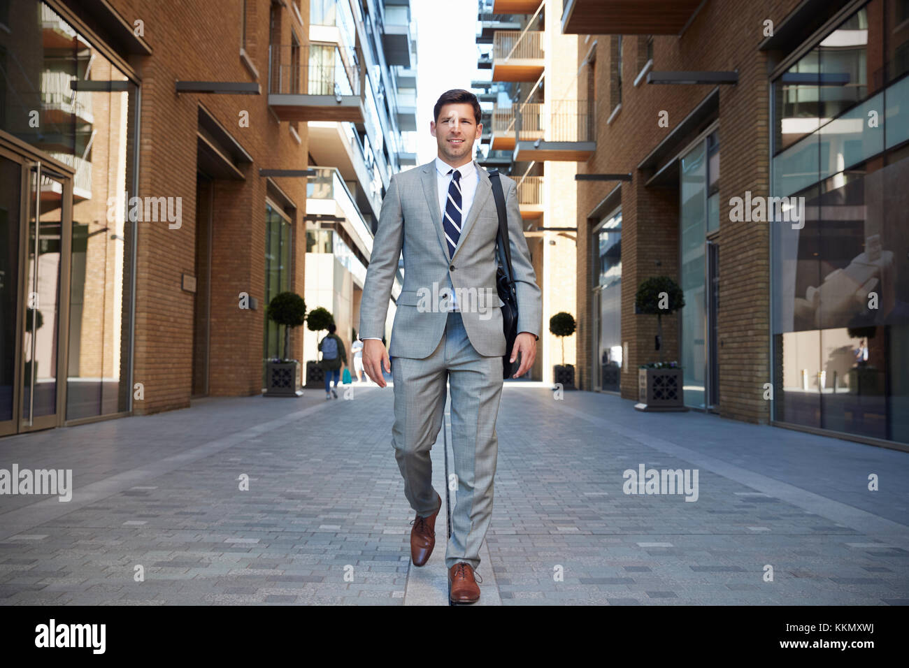 Geschäftsmann zu Fuß zur Arbeit entlang City Street Stockfoto