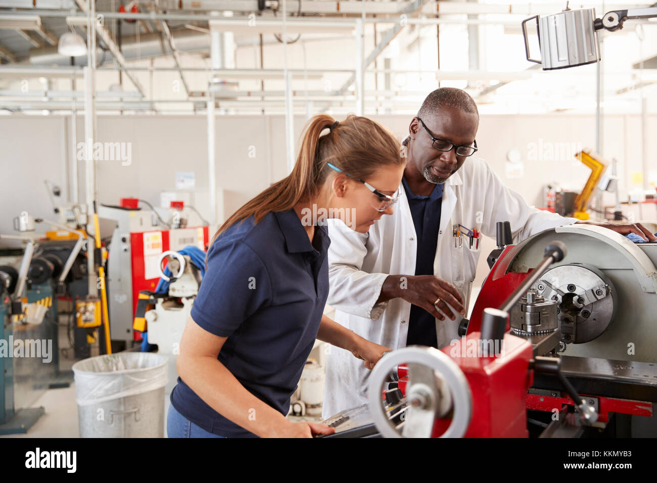 Ingenieur mit weiblichen Lehrling, wie eine Maschine zu bedienen. Stockfoto