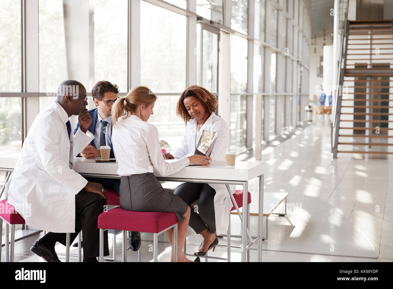 Vier Ärzte auf Laptop in ein modernes Krankenhaus Lobby Stockfoto