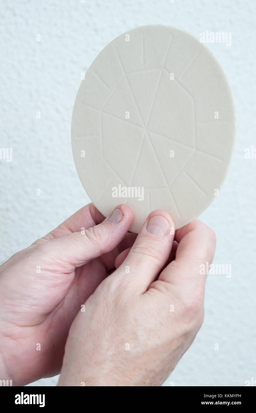 Ein Priester die Hände hält den host Brot, das in der Eucharistie geweiht ist. Teil einer Kirche religiöse Gemeinschaft Zeremonie oder eine Dienstleistung. Stockfoto