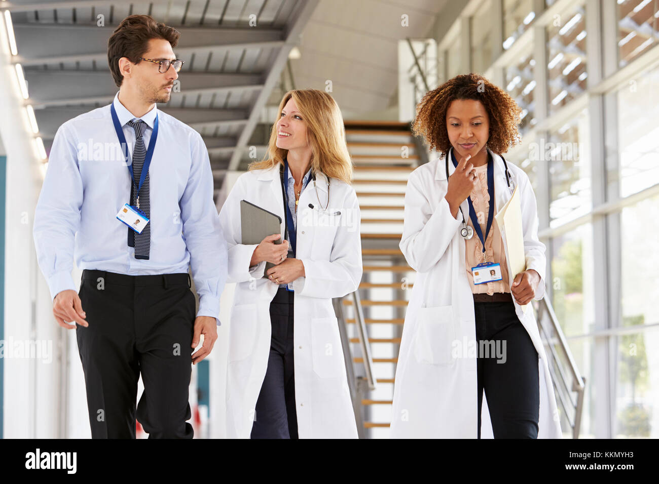 Drei junge männliche und weibliche Ärzte wandern im Krankenhaus Stockfoto