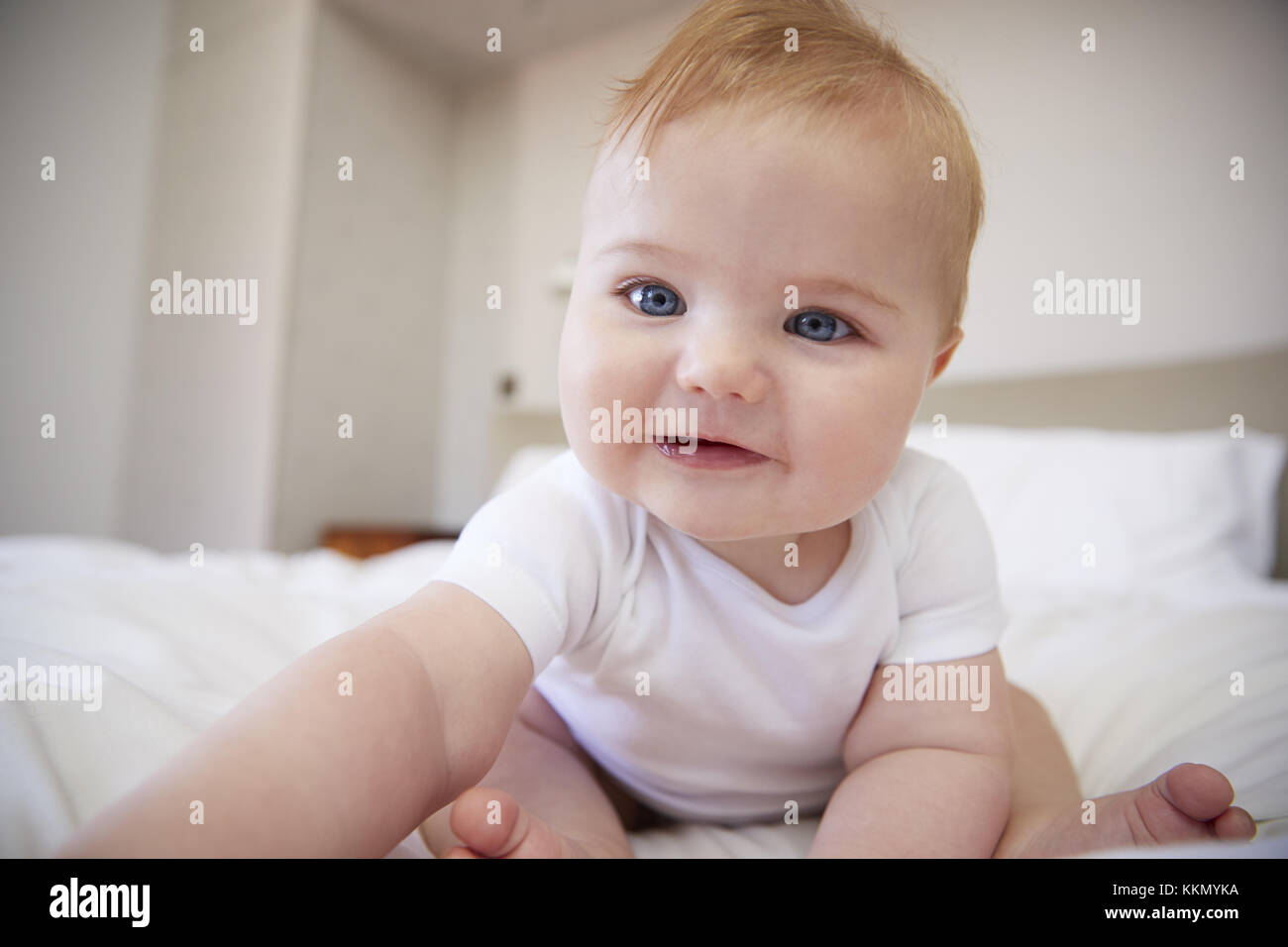 Happy Baby Junge sitzt im Bett der Eltern Stockfoto
