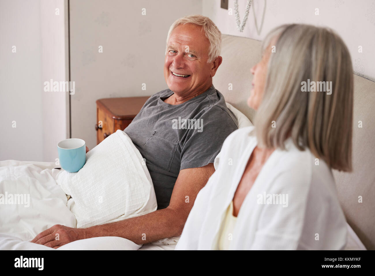 Rentnerehepaar tragen Schlafanzug im Bett sitzen Tee trinken. Stockfoto