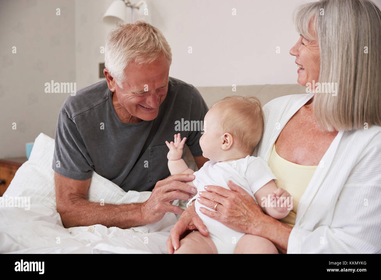 Großeltern Liegen im Bett zu Hause auf der Suche nach Baby Enkel Stockfoto