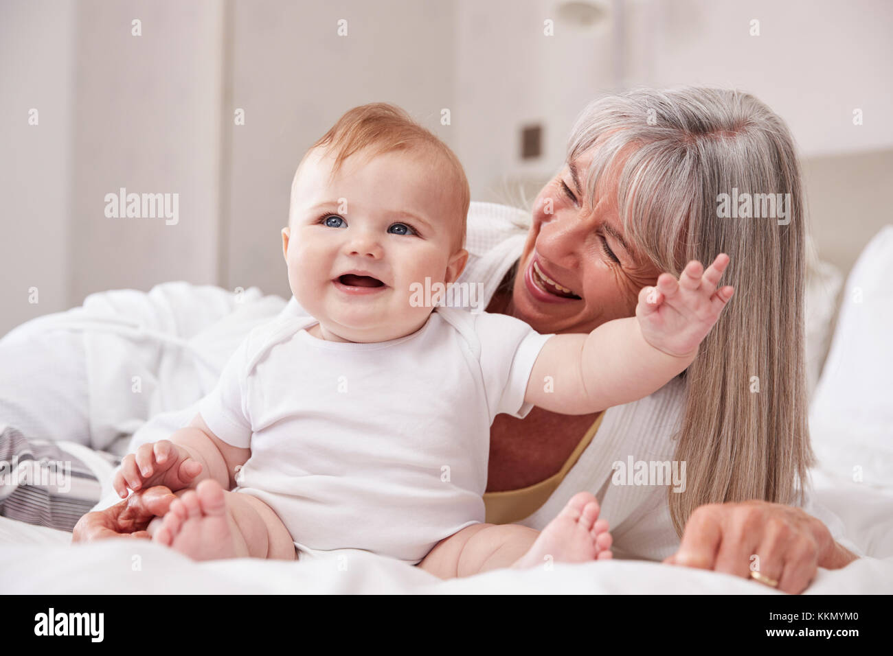 Großmutter im Bett liegend zu Hause auf der Suche nach Baby Enkel Stockfoto