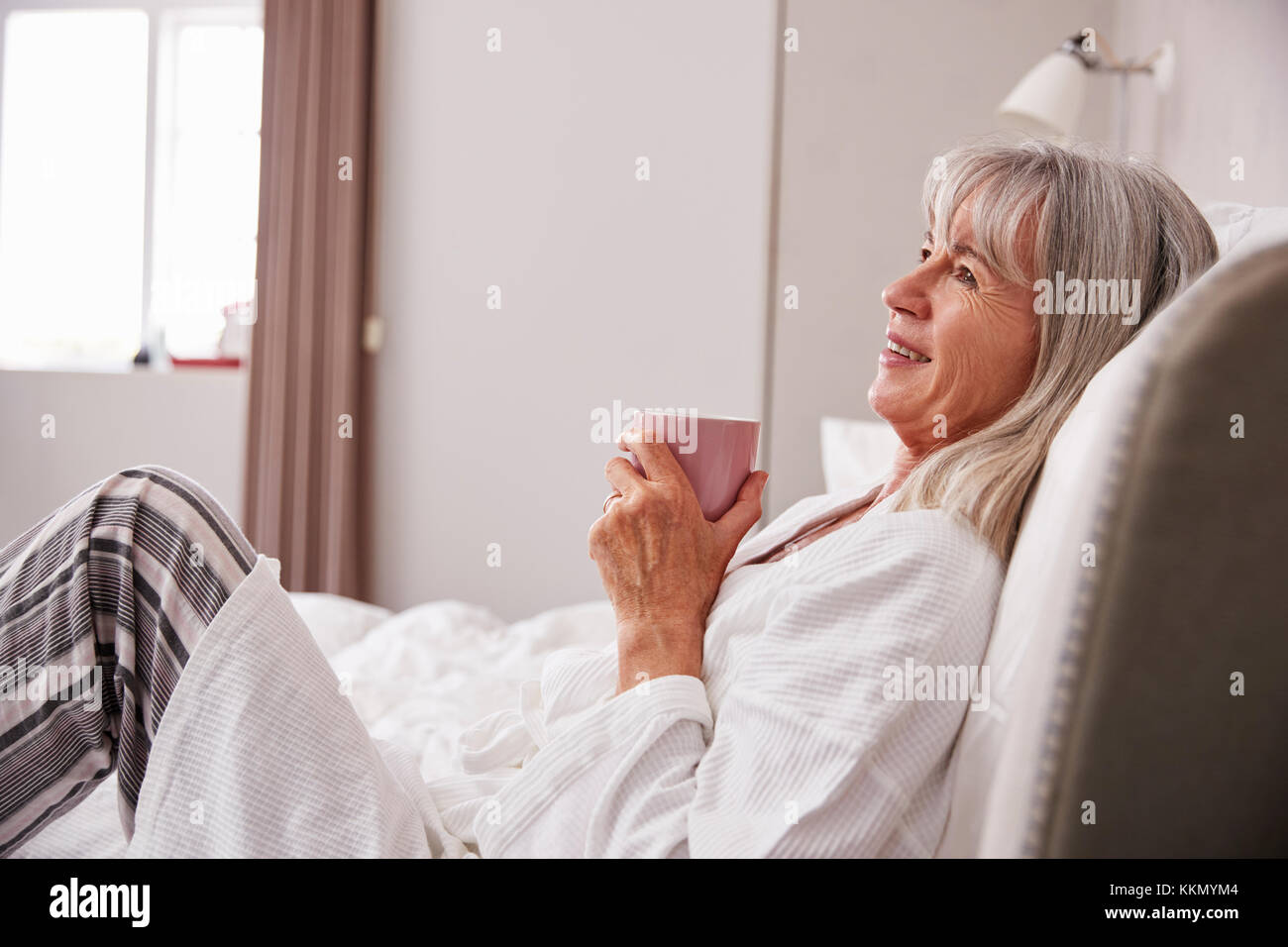 Ältere Frau im Bett mit heißen Getränken Stockfoto