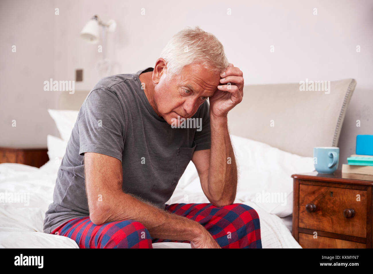 Älterer Mann sitzt auf dem Bett zu Hause, die unter Depressionen leiden Stockfoto