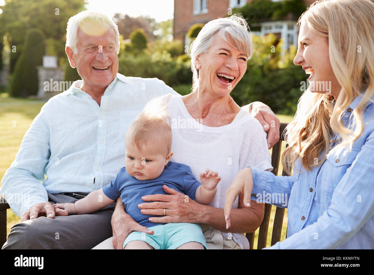 Großeltern Sitzen im Freien mit Baby Enkel und erwachsene Tochter Stockfoto
