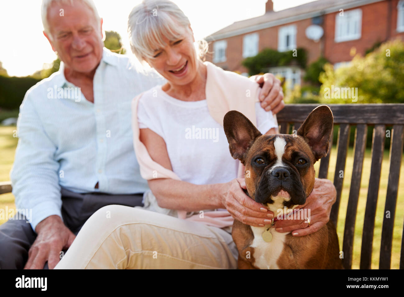 Senior Paar Sitzen auf der Gartenbank Mit Pet-Französische Bulldogge Stockfoto