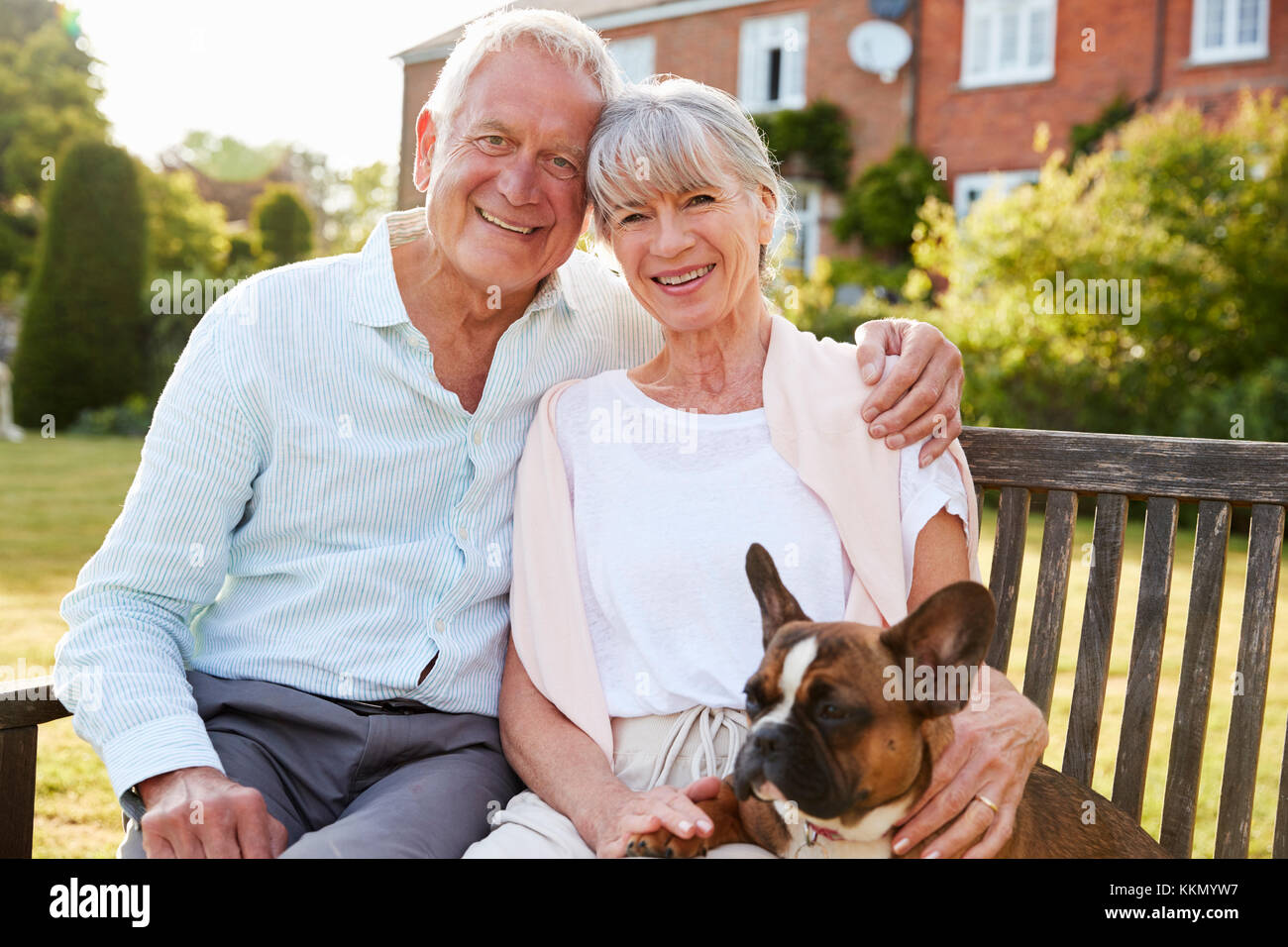 Senior Paar Sitzen auf der Gartenbank Mit Pet-Französische Bulldogge Stockfoto