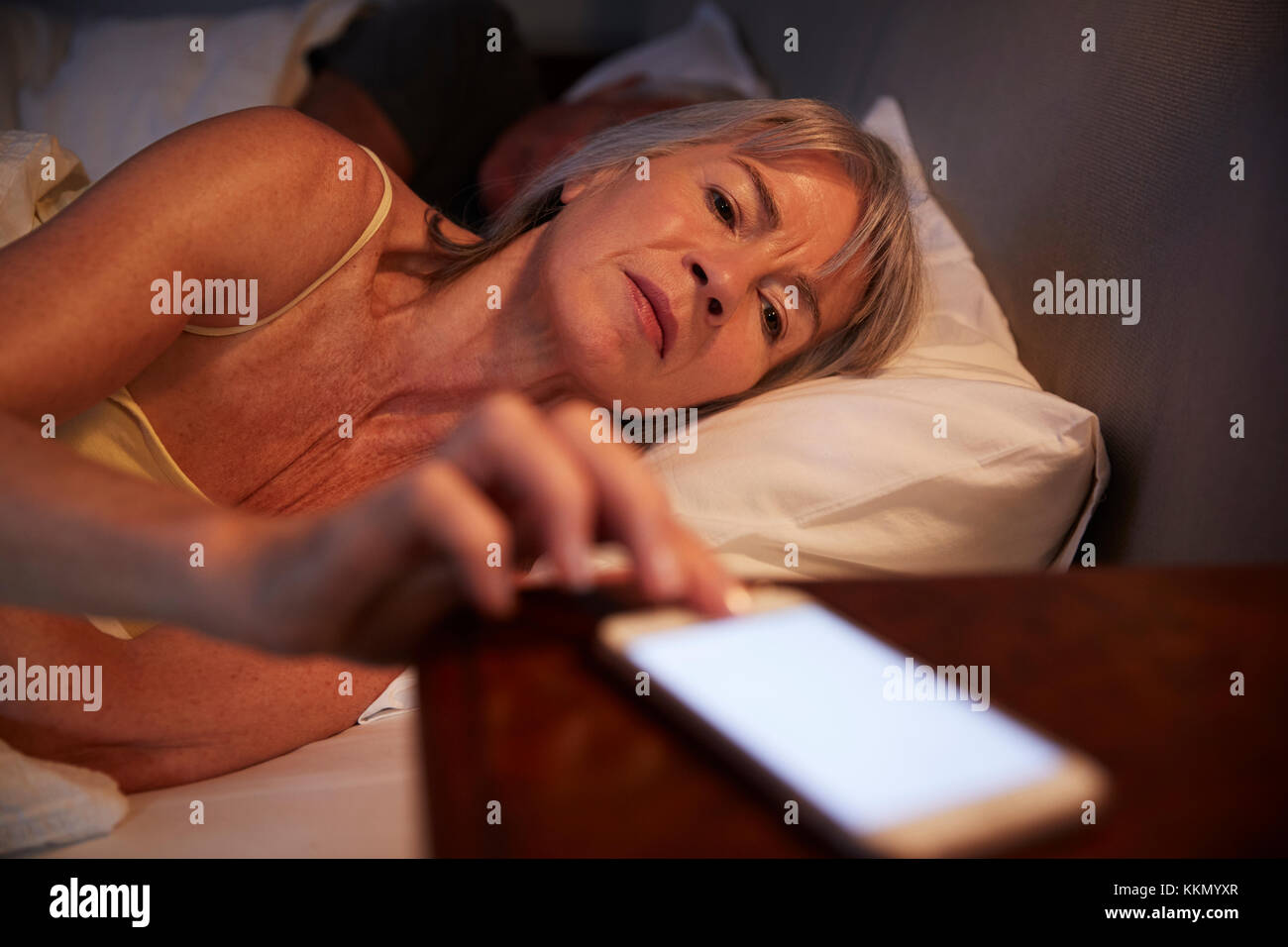 Schlaflose ältere Frau im Bett in der Nacht überprüfen Mobiltelefon Stockfoto