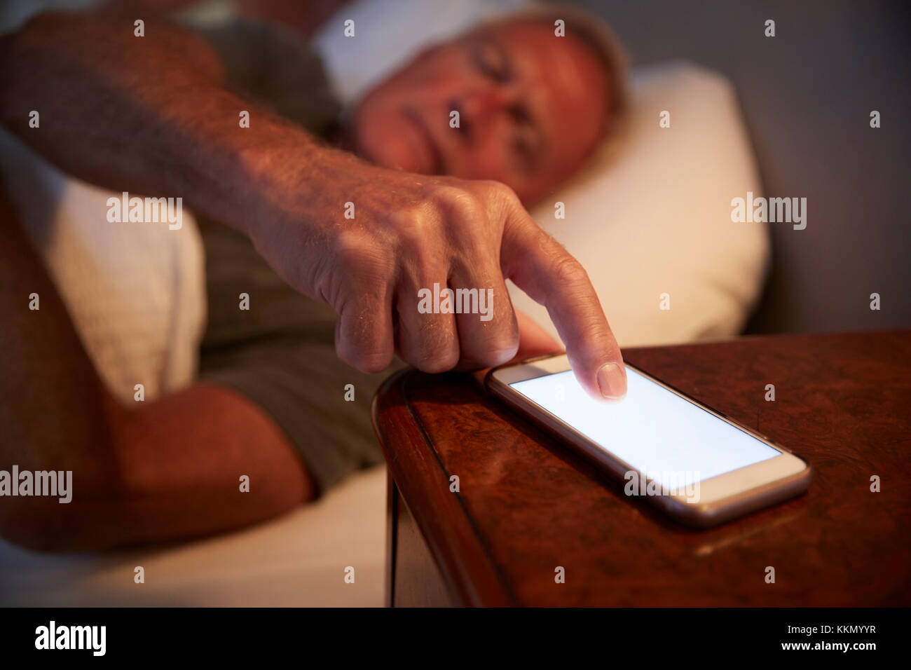 Schlaflose älterer Mann Nachts im Bett Kontrolle Mobiltelefon Stockfoto