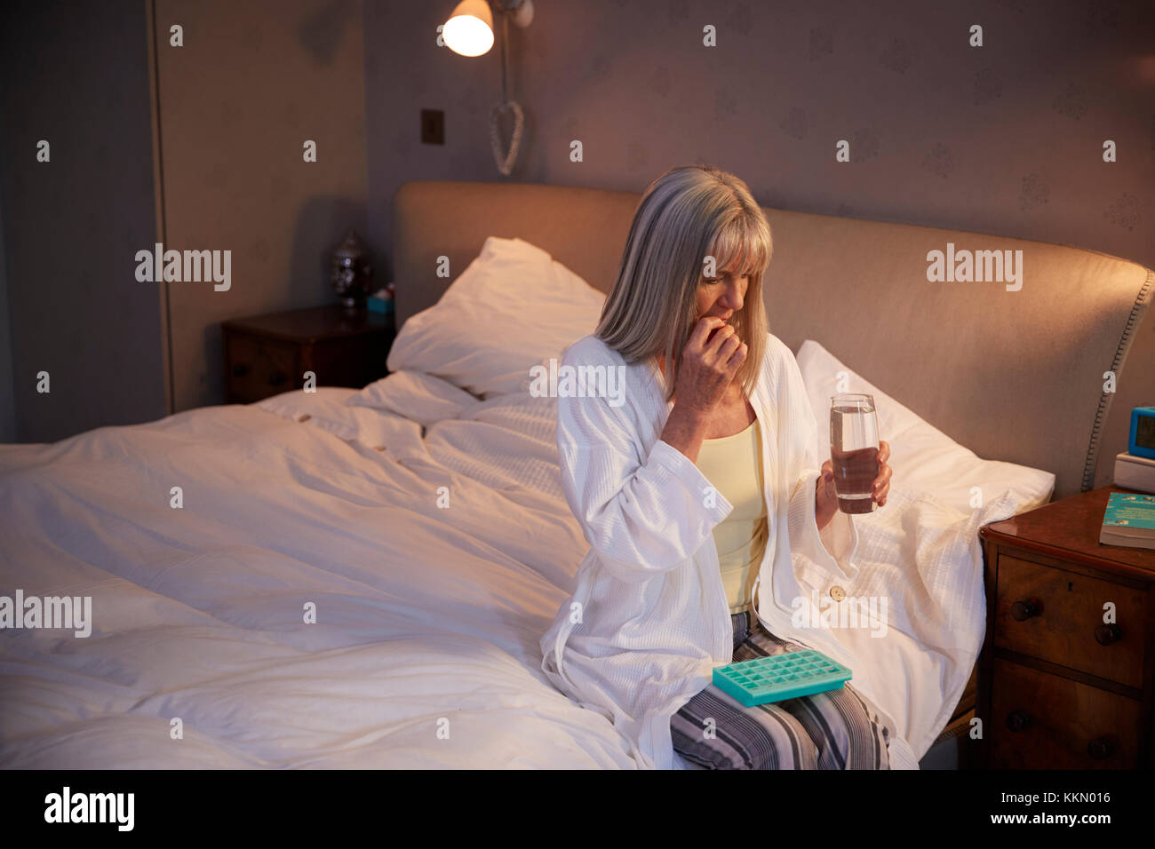 Ältere Frau sitzt am Bett zu Hause Medikamente Stockfoto