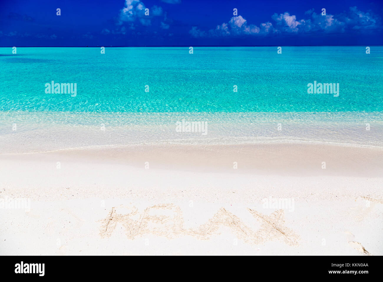 Wort entspannen Sie auf Sand in Malediven mit der Lagune im Hintergrund geschrieben. Stockfoto