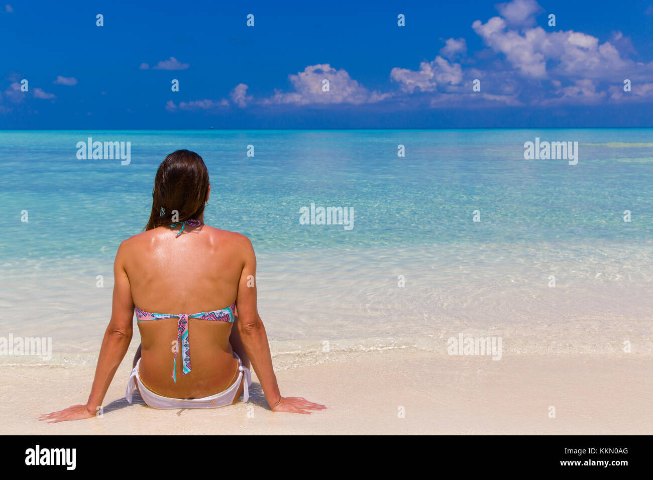 Junge Frau sitzt am Ufer auf den Malediven. Stockfoto