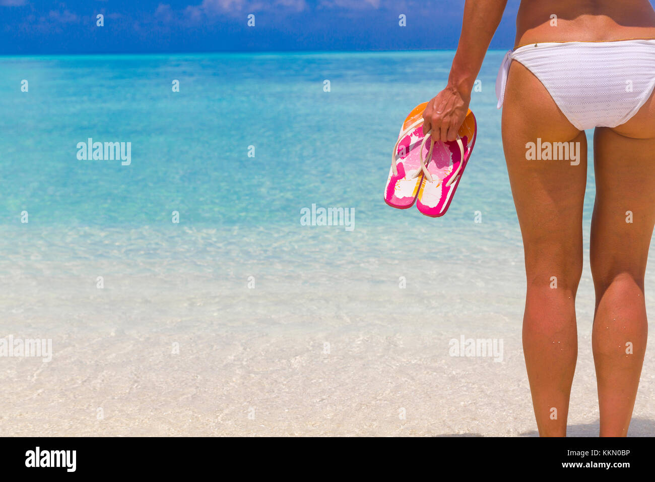 Frau mit Flip Flops beim Stehen auf dem Strand. Stockfoto