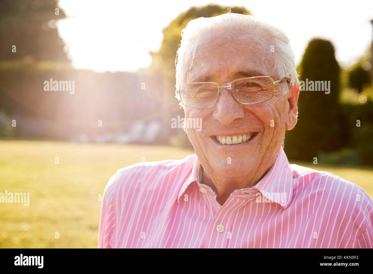 Älterer Mann im Garten lächelnd in die Kamera, in der Nähe Stockfoto