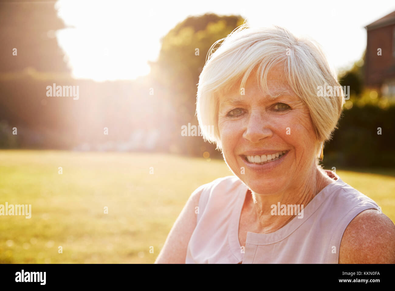 Ältere Frau im Garten, ein Lächeln für die Kamera, in der Nähe Stockfoto