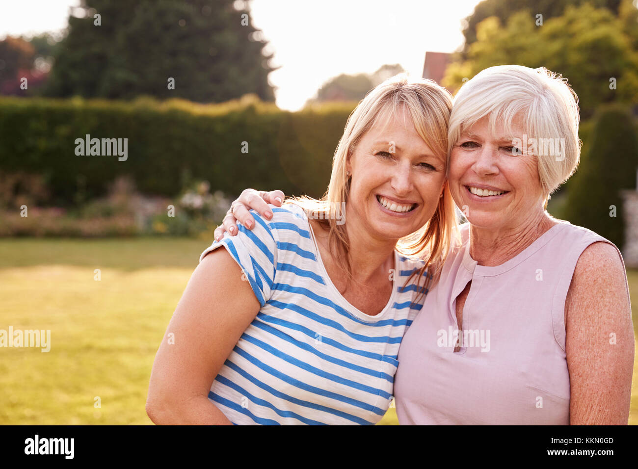 Ältere Frau und erwachsene Tochter umarmen im Garten Stockfoto