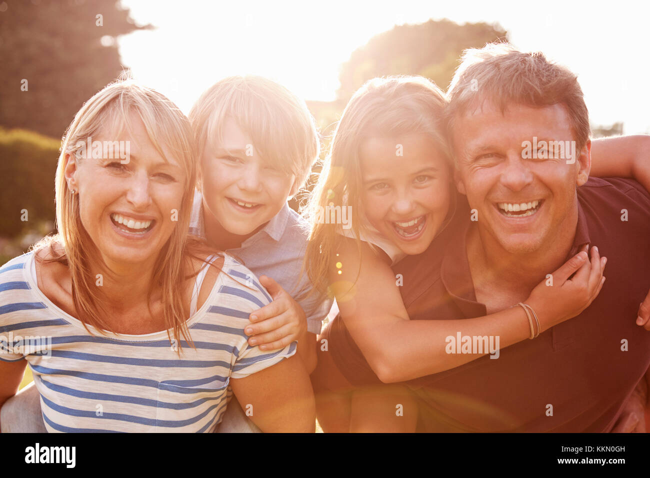 Paar mittleren Alters huckepack ihre Kinder Lächeln für die Kamera Stockfoto