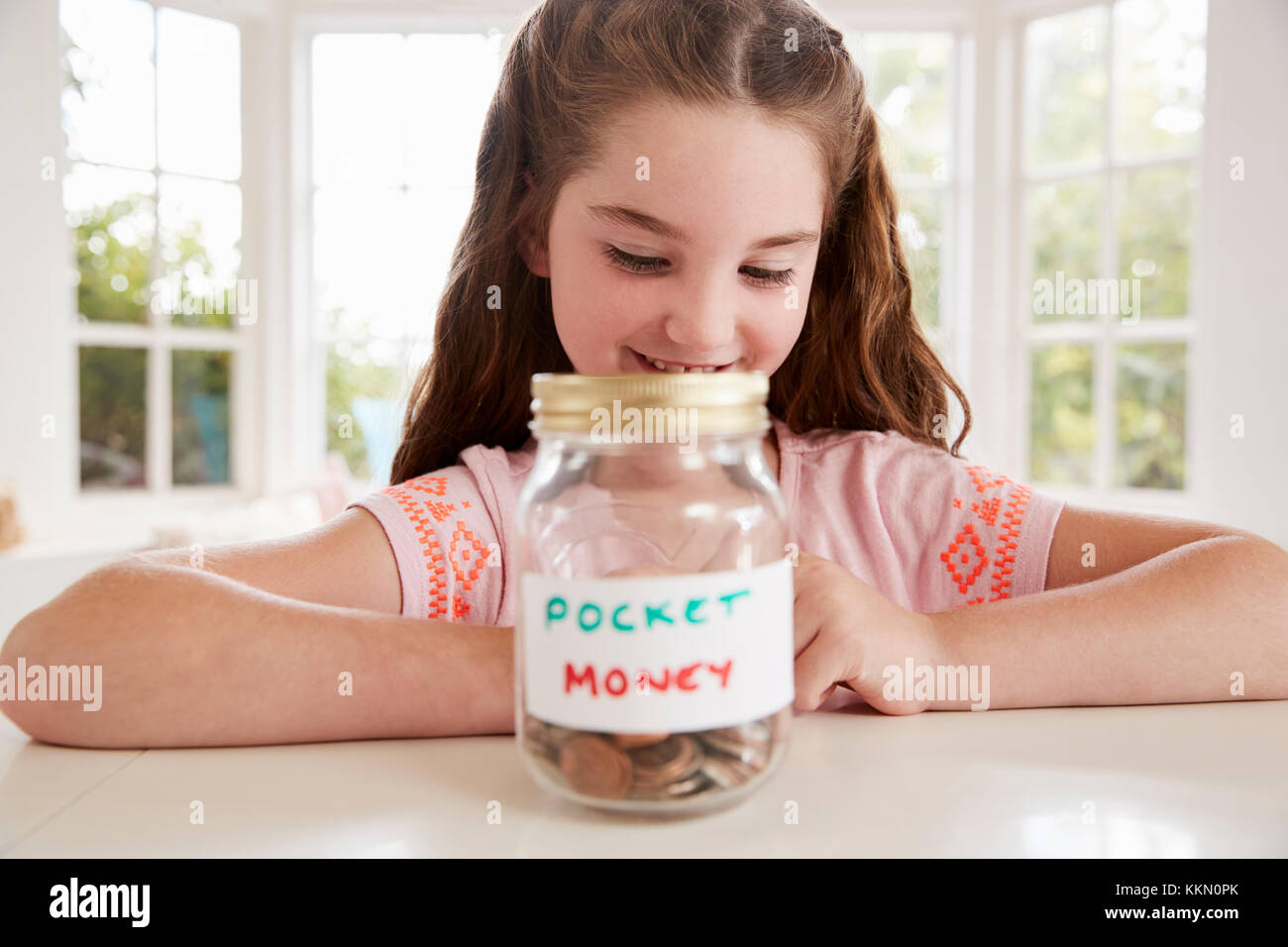 Mädchen speichern Taschengeld in Glas zu Hause Stockfoto