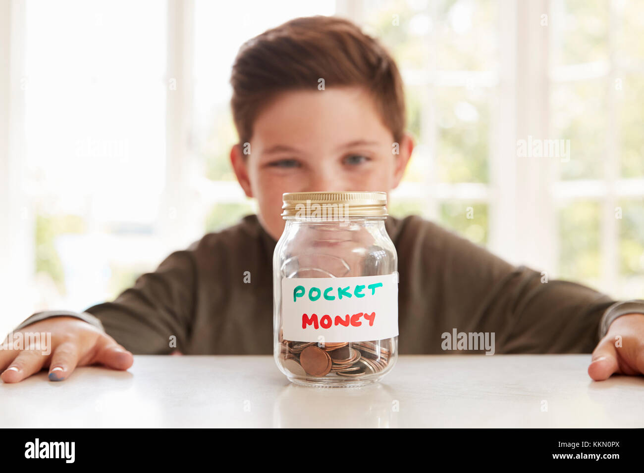 Junge speichern Taschengeld in Glas zu Hause Stockfoto