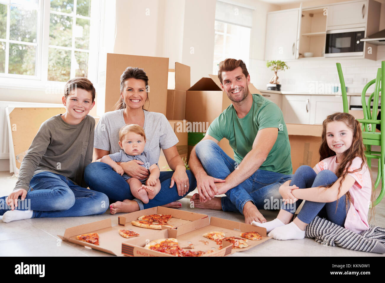 Porträt der Familie feiert Umzug in neues Haus mit Pizza Stockfoto