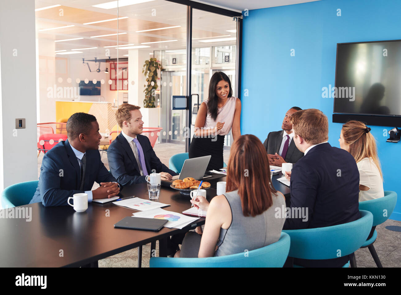 Weibliche Manager steht mit Kollegen im Tagungsraum Stockfoto