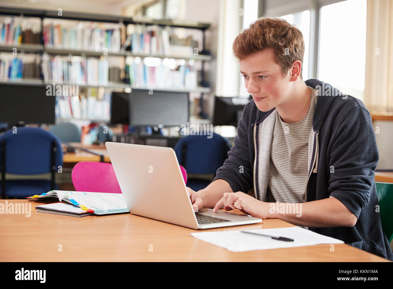 Männliche Kursteilnehmer Arbeiten am Laptop in der Hochschule Bibliothek Stockfoto