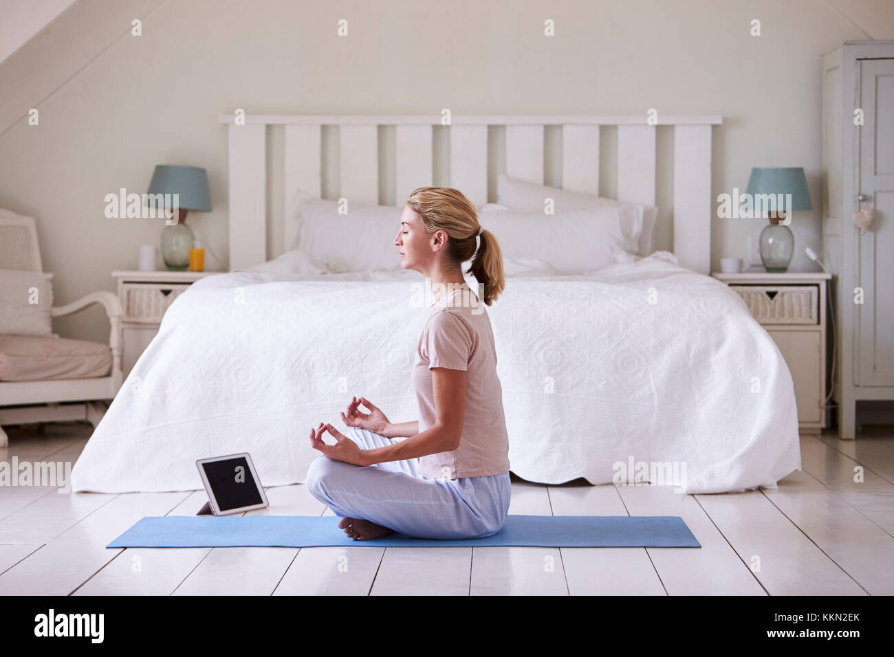 Frau mit digitalen Tablet mit Meditation App im Schlafzimmer Stockfoto