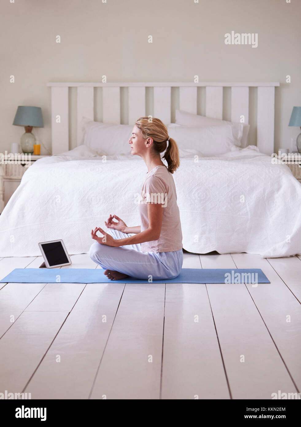 Frau mit digitalen Tablet mit Meditation App im Schlafzimmer Stockfoto