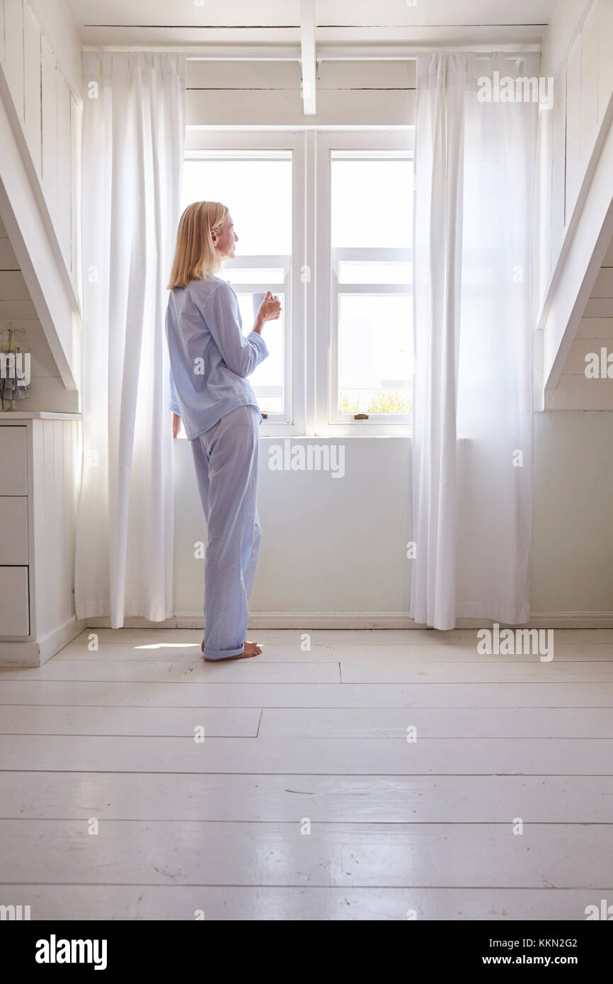 Frau von Schlafzimmer Fenster mit heißen Getränken Stockfoto