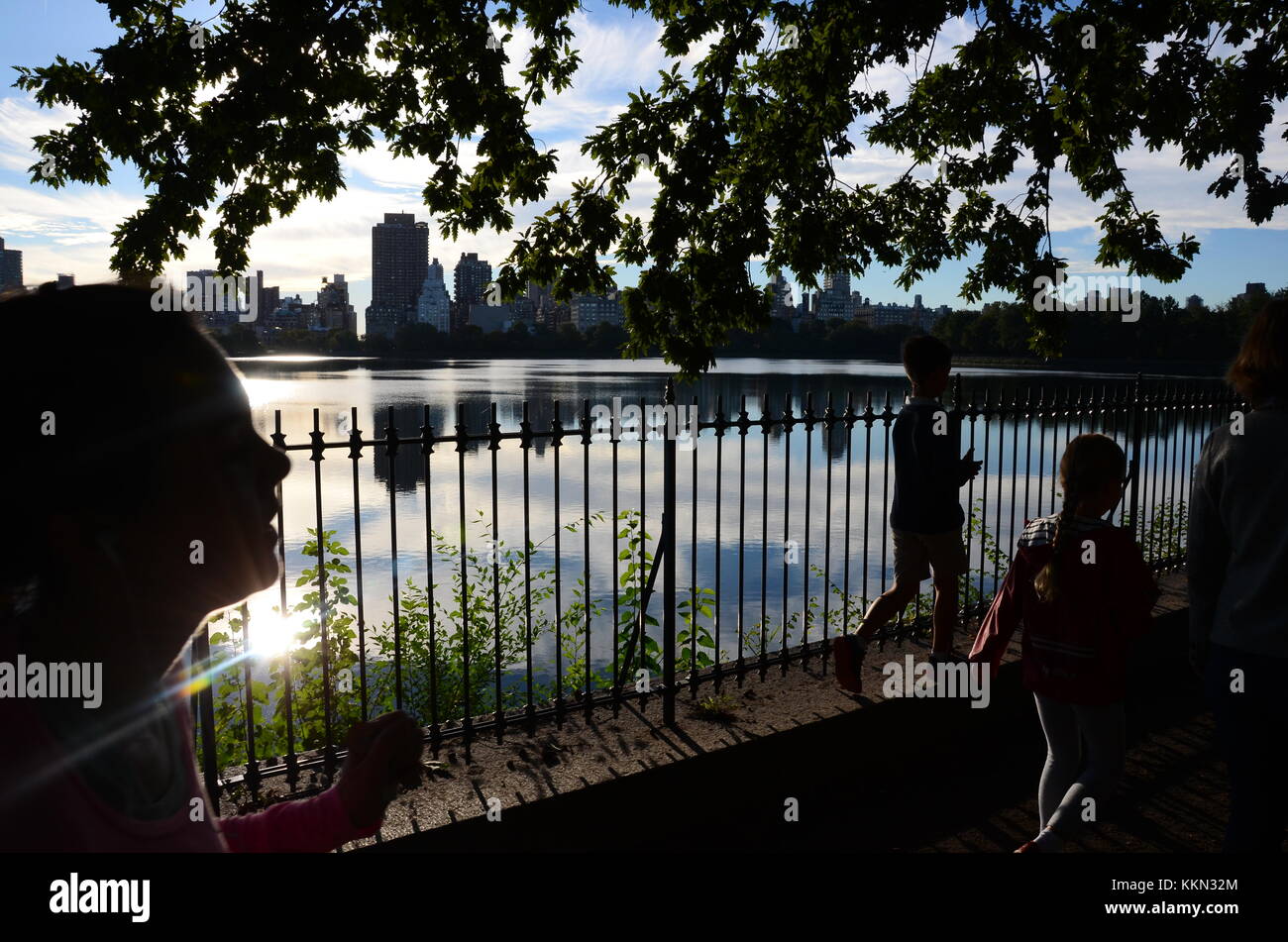 Jogger laufen um den Jackie Kennedy-Onassis Vorratsbehälter auf dem Schuman Laufstrecke im Central Park in New York City von der Sonne. Stockfoto