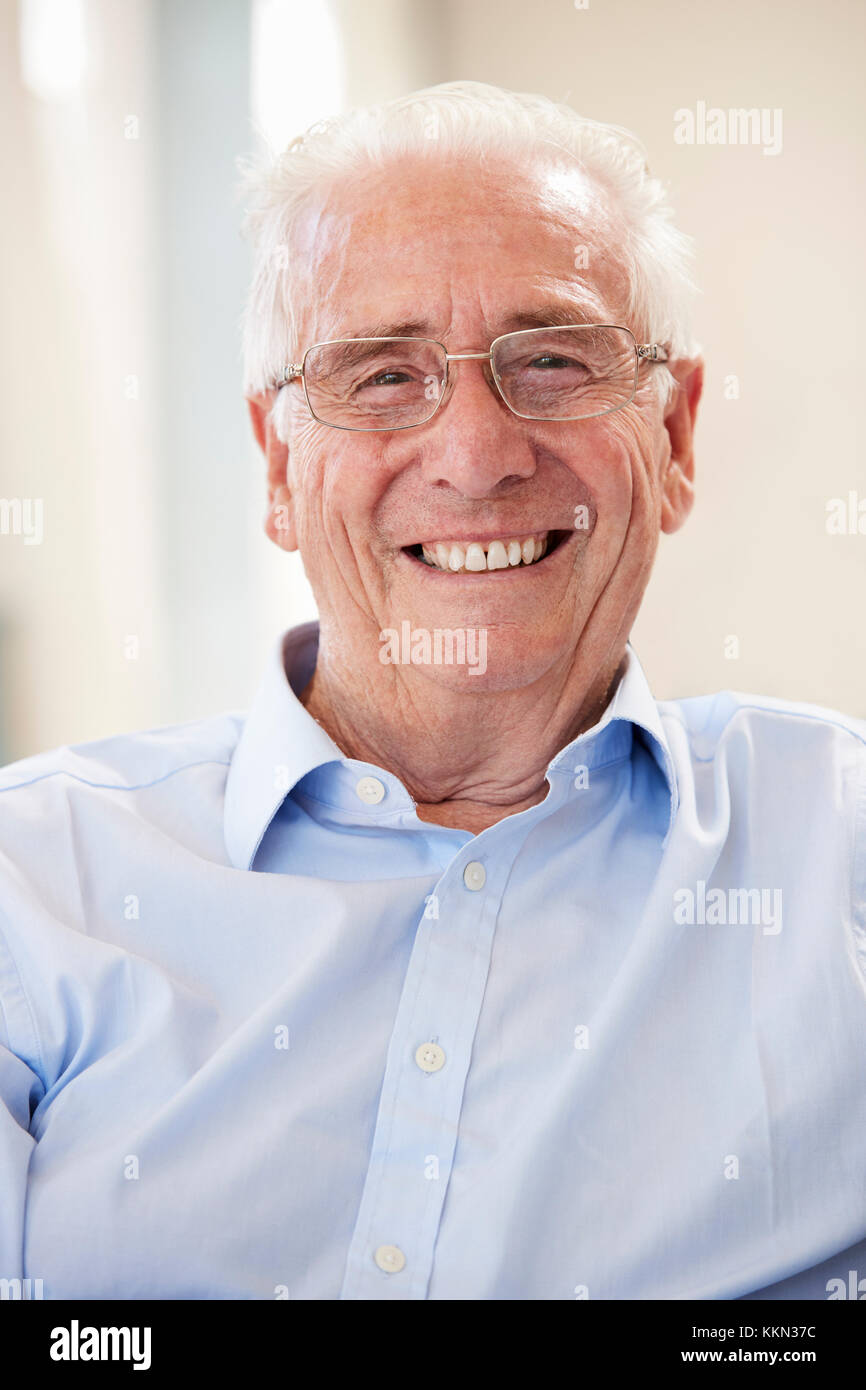 Portrait Of Smiling Senior Mann zu Hause auf dem Sofa sitzen Stockfoto