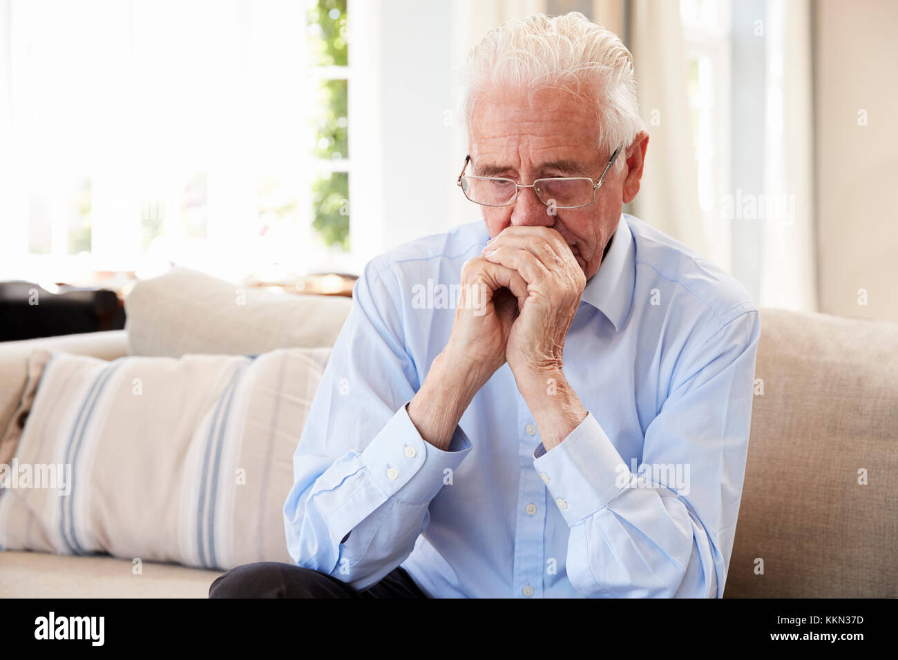 Älterer Mann sitzt auf einem Sofa zu Hause, die unter Depressionen leiden Stockfoto