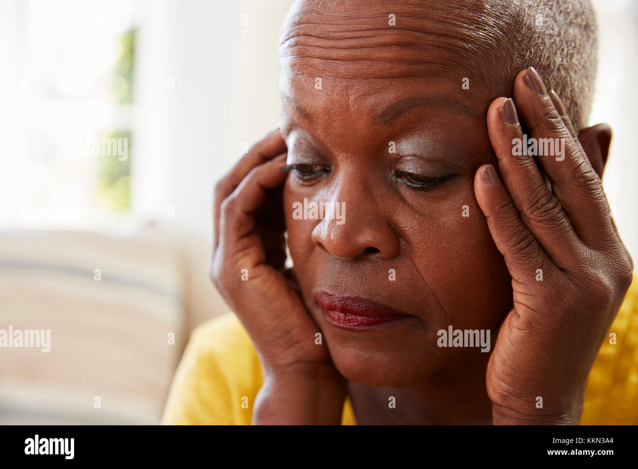 Ältere Frau sitzt auf einem Sofa zu Hause, die unter Depressionen leiden Stockfoto