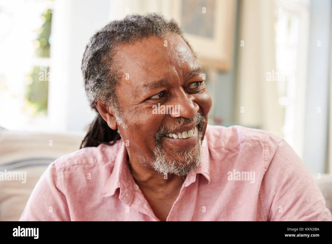 Lächelnder Senior Mann zu Hause auf dem Sofa sitzen Stockfoto