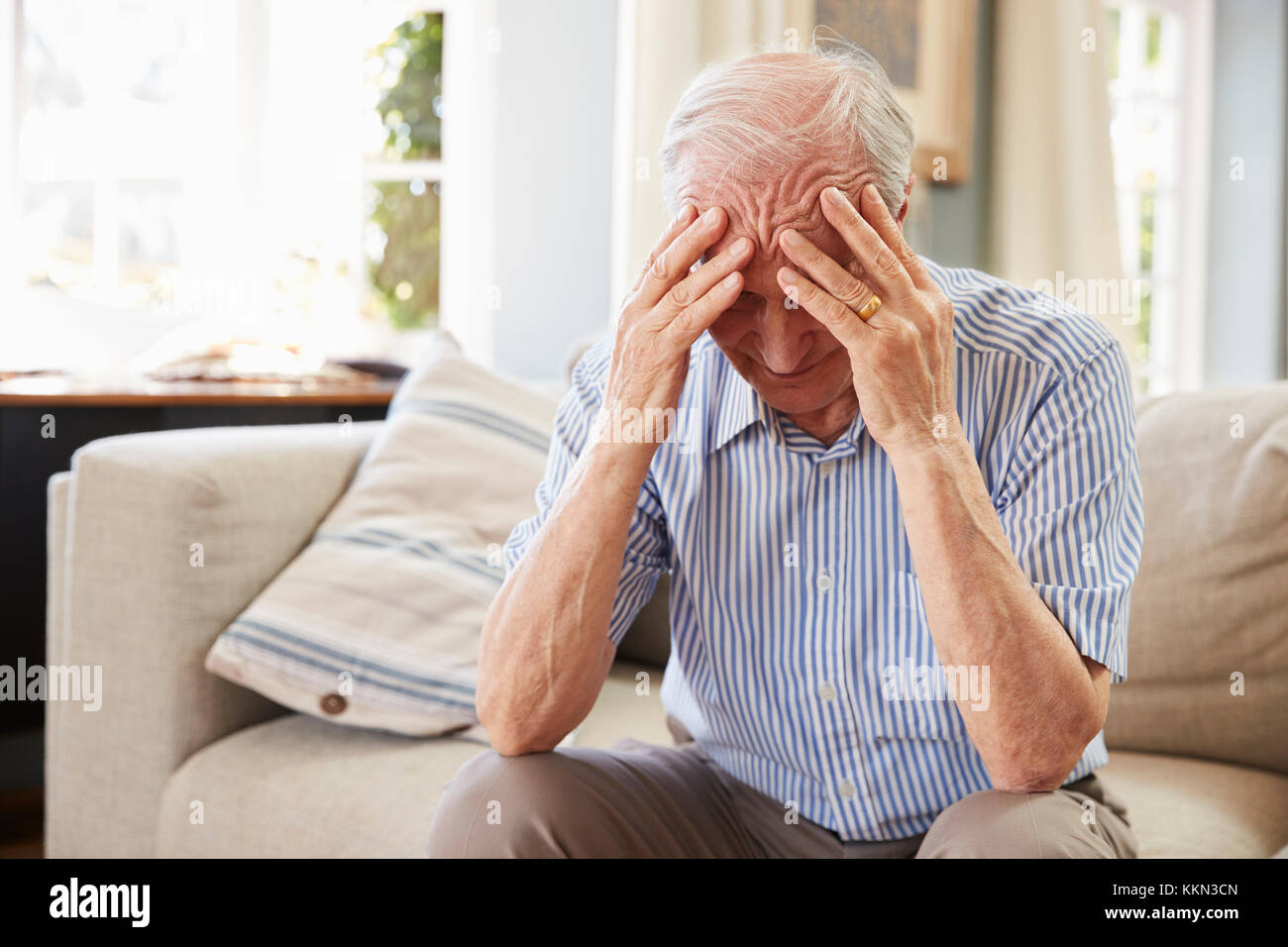 Älterer Mann sitzt auf einem Sofa zu Hause, die unter Depressionen leiden Stockfoto