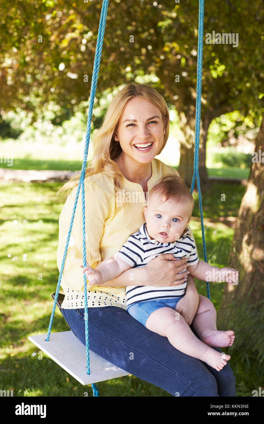 Porträt der Mutter spielt mit Baby Sohn auf Gartenschaukel Stockfoto