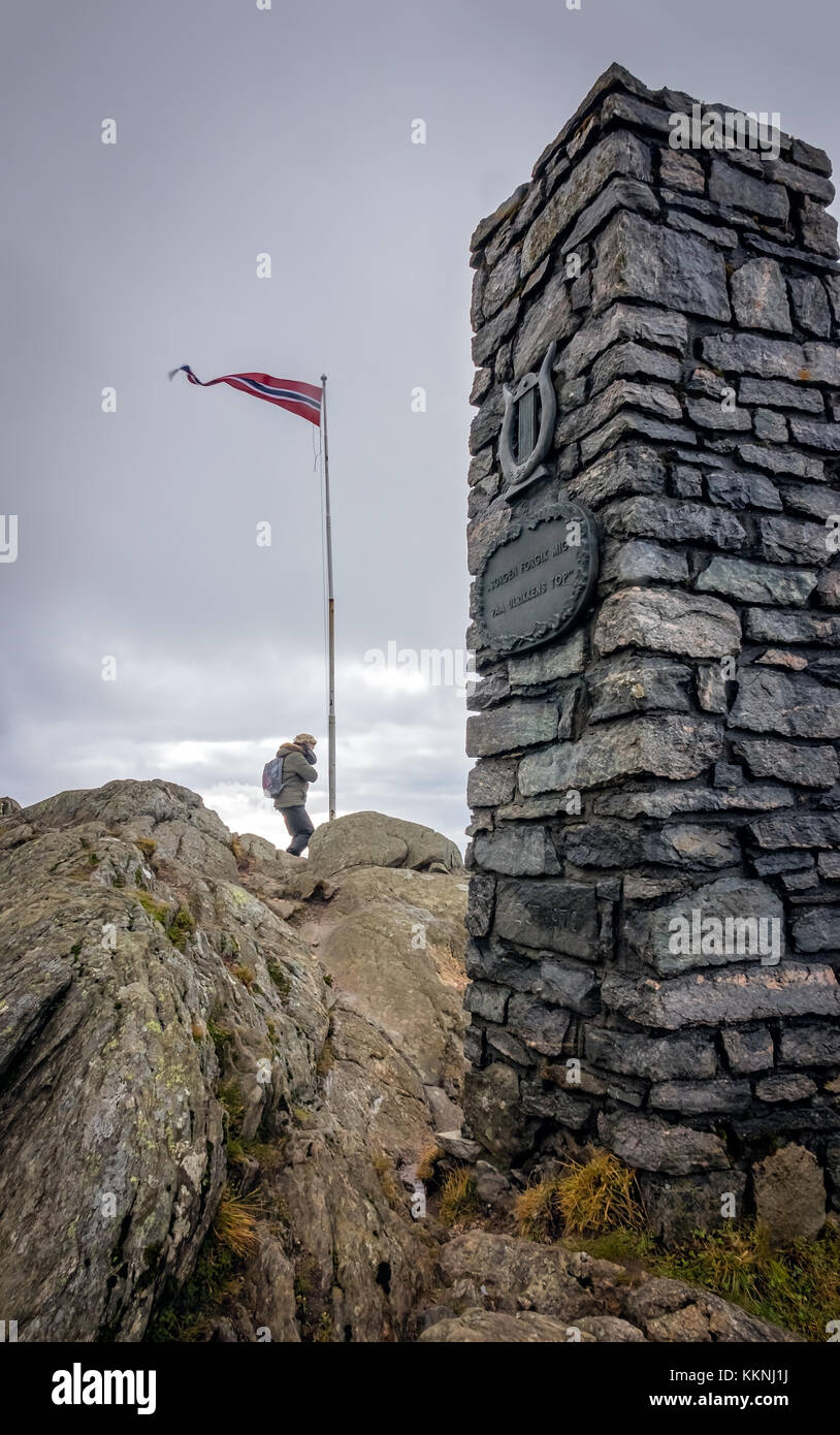 Bergen, Norwegen - Oktober 2017: Touristische unter die norwegische Flagge Pole und Stein Denkmal auf dem Gipfel des Mount Ulriken, Bergen, Norwegen Stockfoto