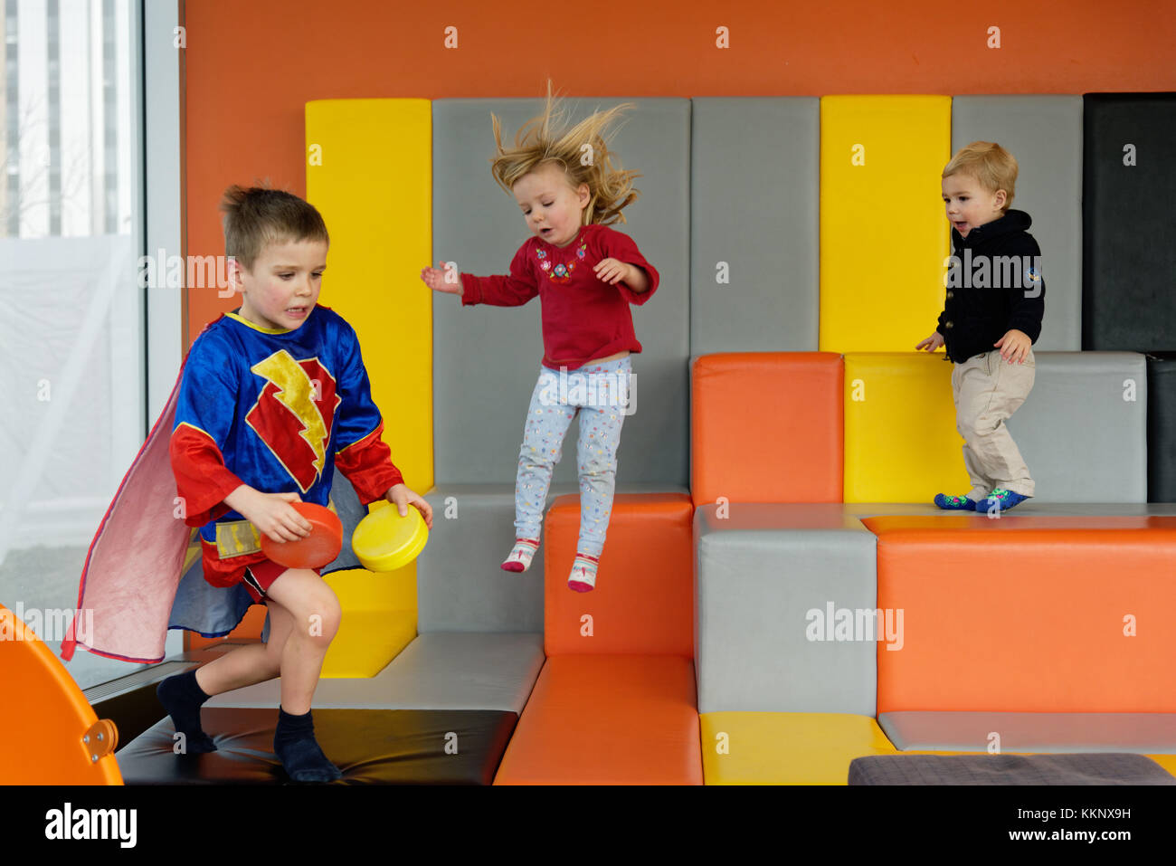 Kinder spielen und Springen in einen gepolsterten Spielbereich Stockfoto