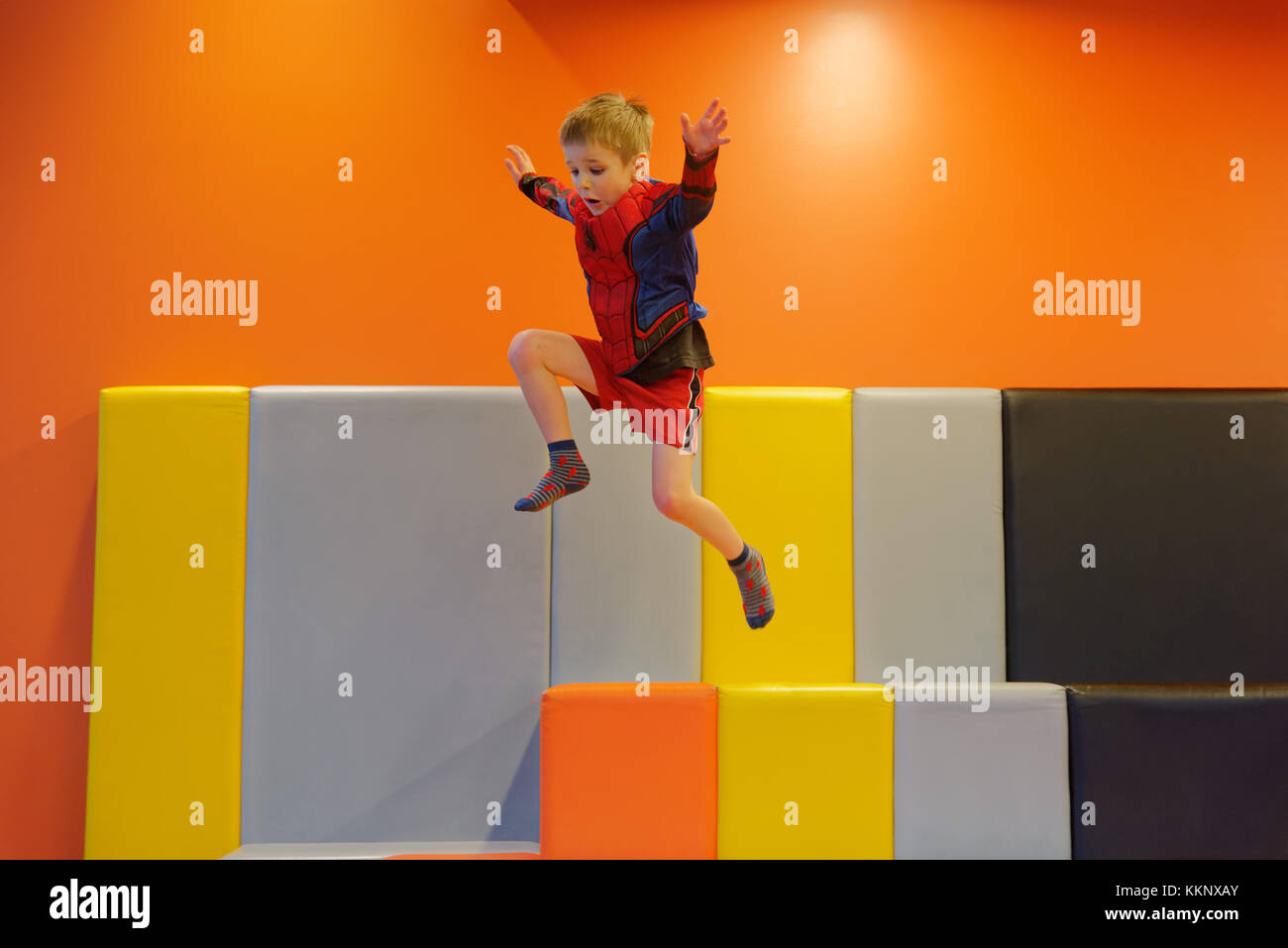 Ein kleiner Junge (5 Jahre alt) das Springen in einem gepolsterten Spielbereich Stockfoto
