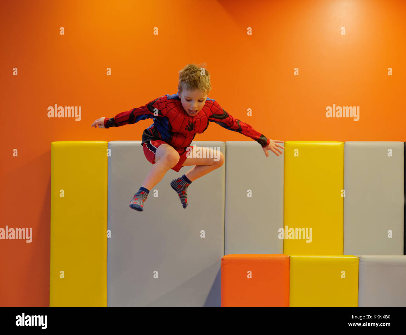 Ein kleiner Junge (5 Jahre alt) das Springen in einem gepolsterten Spielbereich Stockfoto