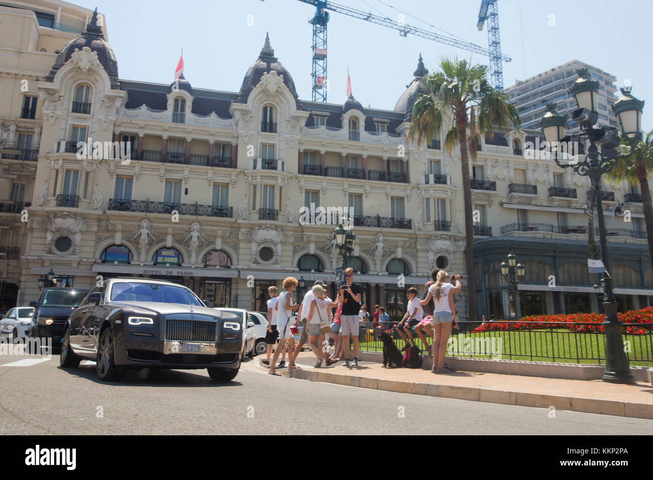 Touristen fotografieren in Casino Square, Monaco als ein Rolls Royce fährt aber mit einem Hintergrund von Hotel De Paris Stockfoto